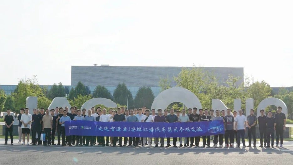 Guests participating in a group photo in front of the NIO factory